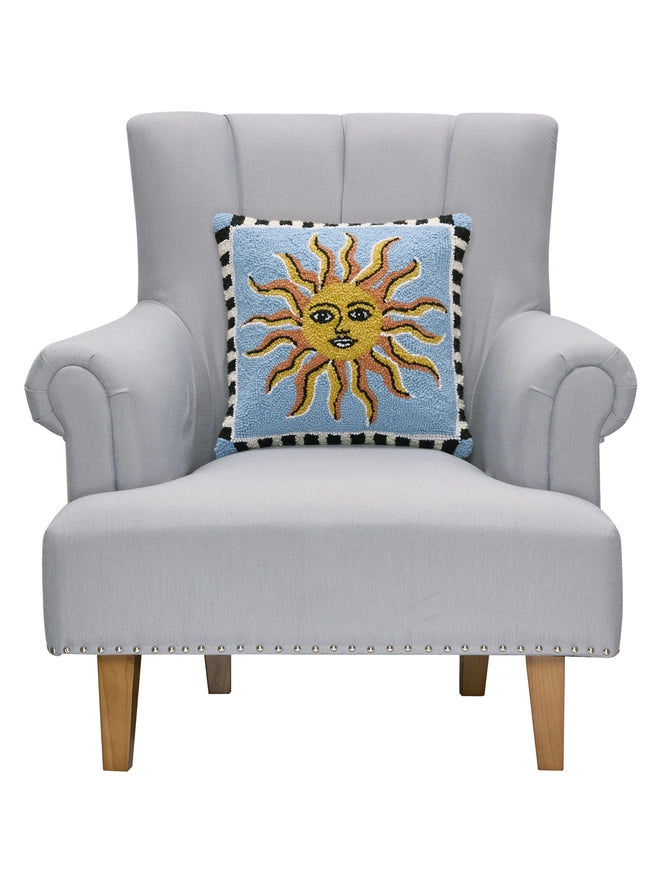 Gray armchair with a decorative pillow featuring a sun design on a white background